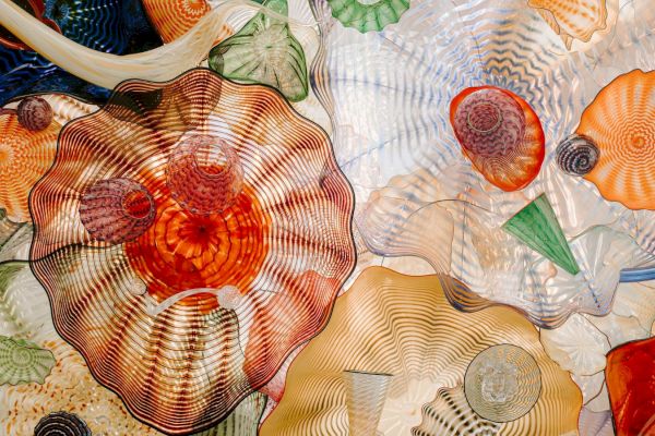 This image shows a collection of colorful, intricately designed glass sculptures with various patterns and shapes, creating a vibrant, artistic display.