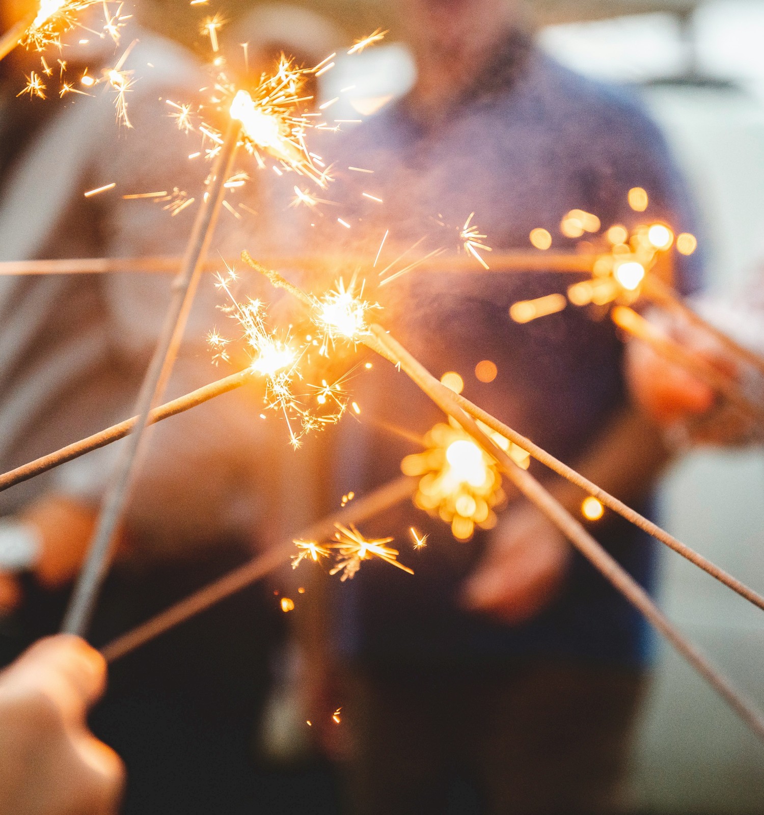 A group of people holding lit sparklers together, creating a festive and celebratory atmosphere.